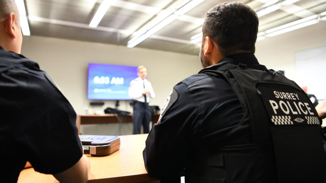 officers sitting at table watching Chief Constable speak