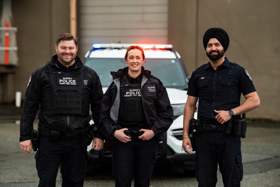 Three police officers standing by a police car