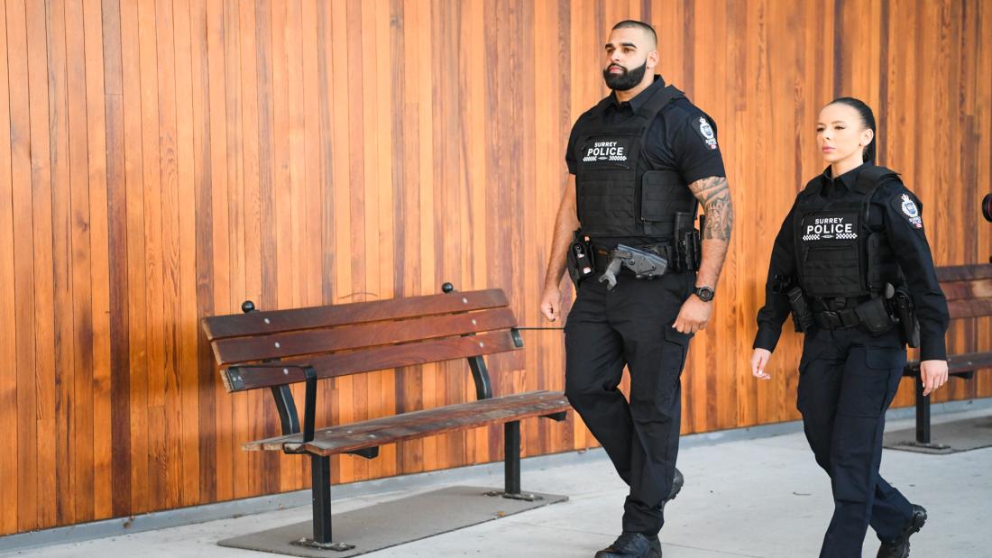 Two Surrey Police Officers in Uniform walking in front of building 