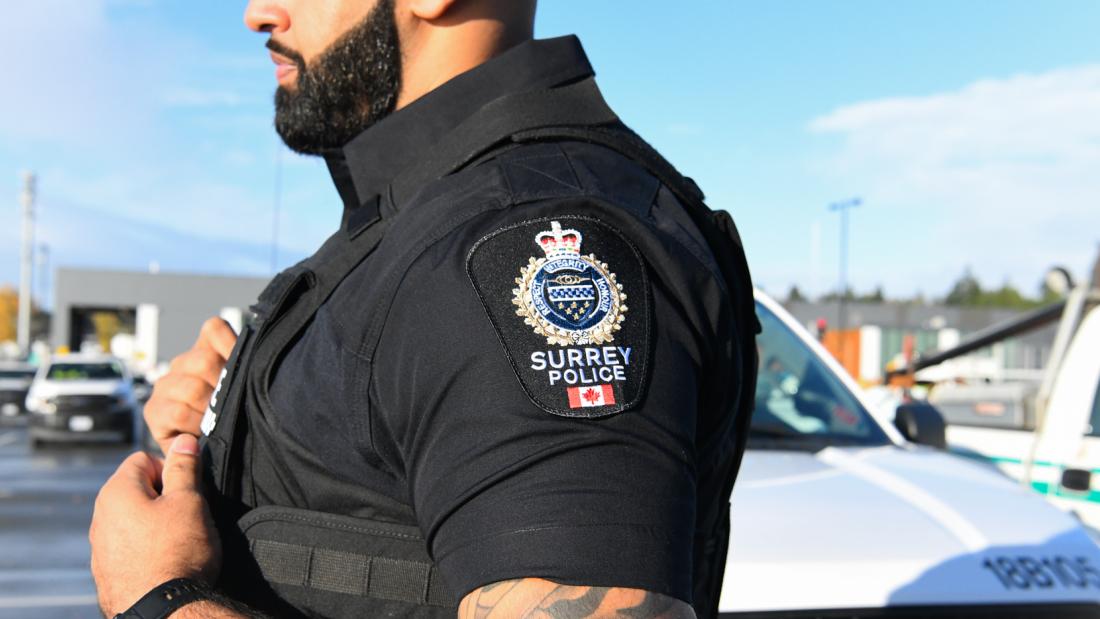 SPS Officer in uniform stands in front of vehicle 