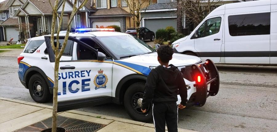 Kid in front of a cop car